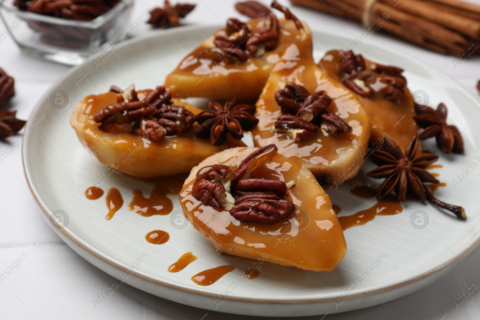 Photo of Delicious pears with caramel sauce, pecan nuts and anise stars on white table, closeup