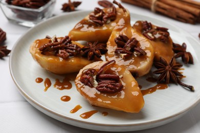 Photo of Delicious pears with caramel sauce, pecan nuts and anise stars on white table, closeup