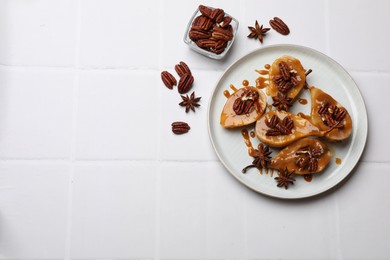 Photo of Delicious pears with caramel sauce, pecan nuts and anise stars on white tiled table, top view. Space for text