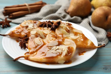 Delicious pears with caramel sauce, almond flakes and anise stars on light blue wooden table, closeup