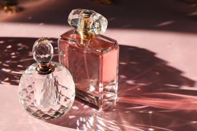 Photo of Beautiful perfume bottles on light pink background with shadow, closeup