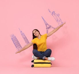 Image of Happy traveler sitting on suitcase and spreading hands as airplane wings on pink background. Illustration of famous landmarks over her arms