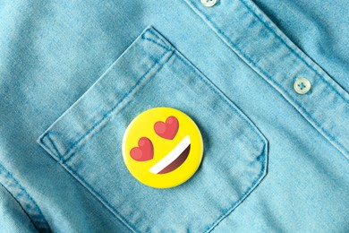 Image of Badge with heart-eyes face attached to pocket of denim shirt