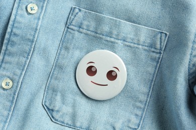 Image of Badge with smiling face attached to pocket of denim shirt