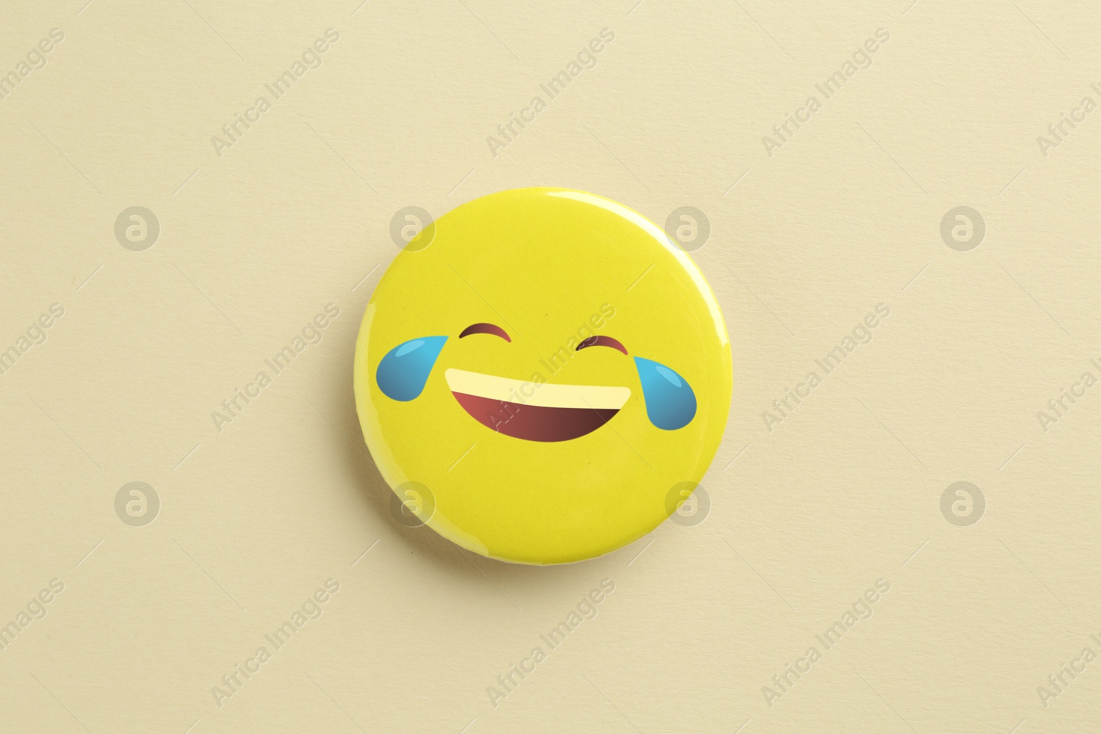 Image of Badge displaying laughing face with tears on beige background