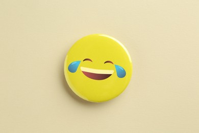 Badge displaying laughing face with tears on beige background