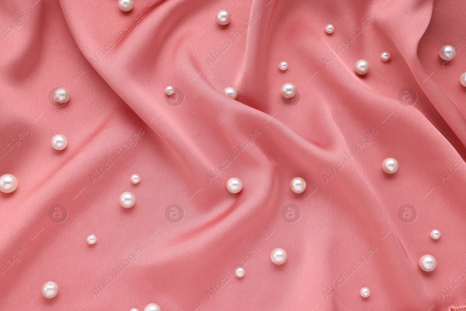 Photo of Many elegant pearls on pink fabric, top view