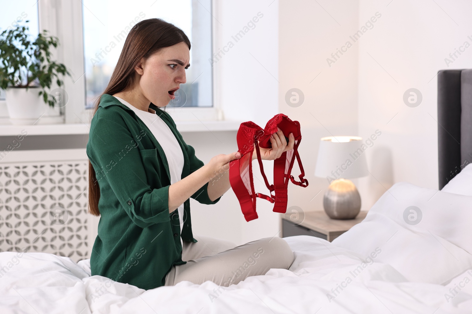 Photo of Surprised wife finding mistress bra in bedroom