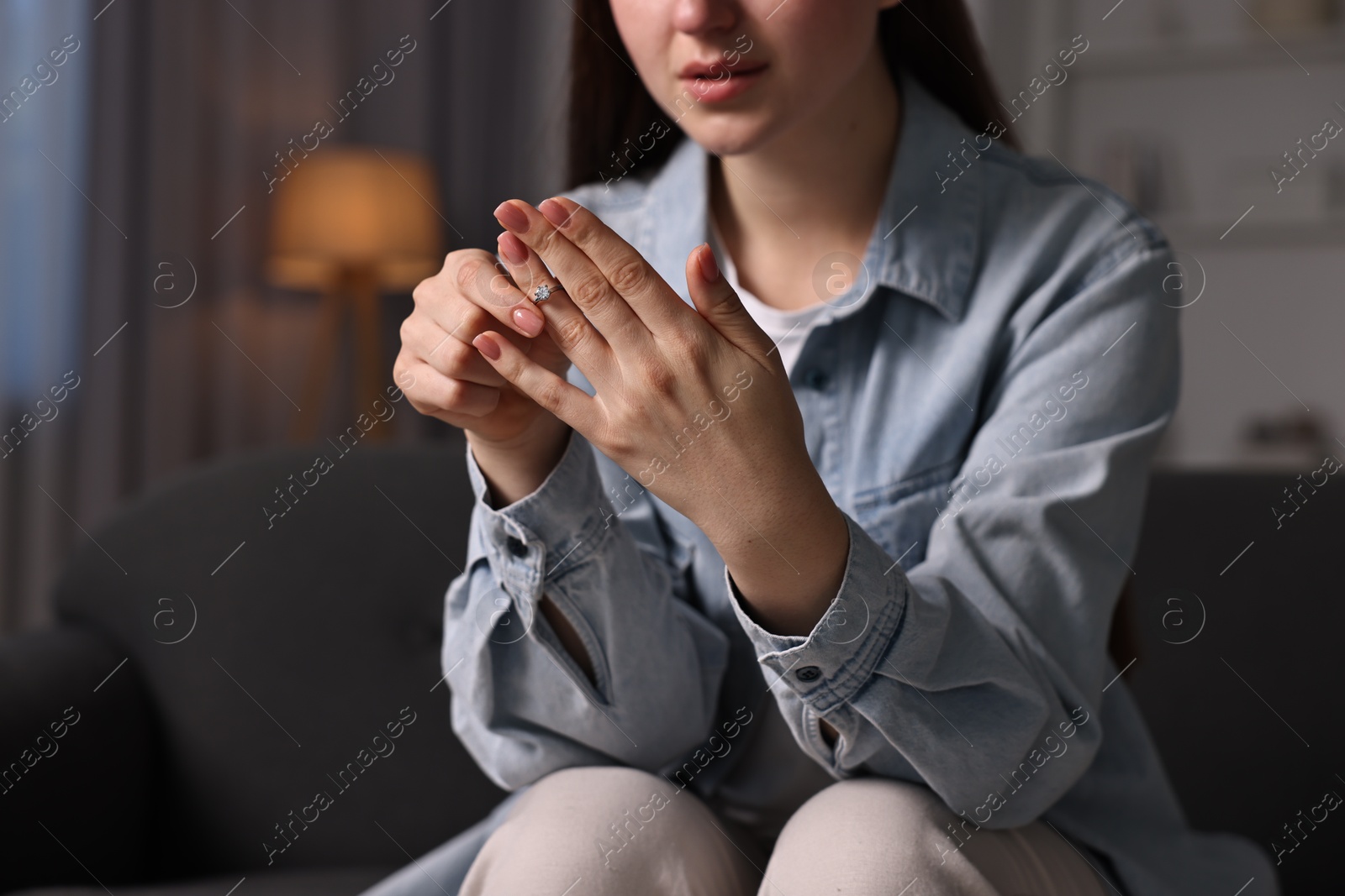 Photo of Woman taking off engagement ring at home, closeup