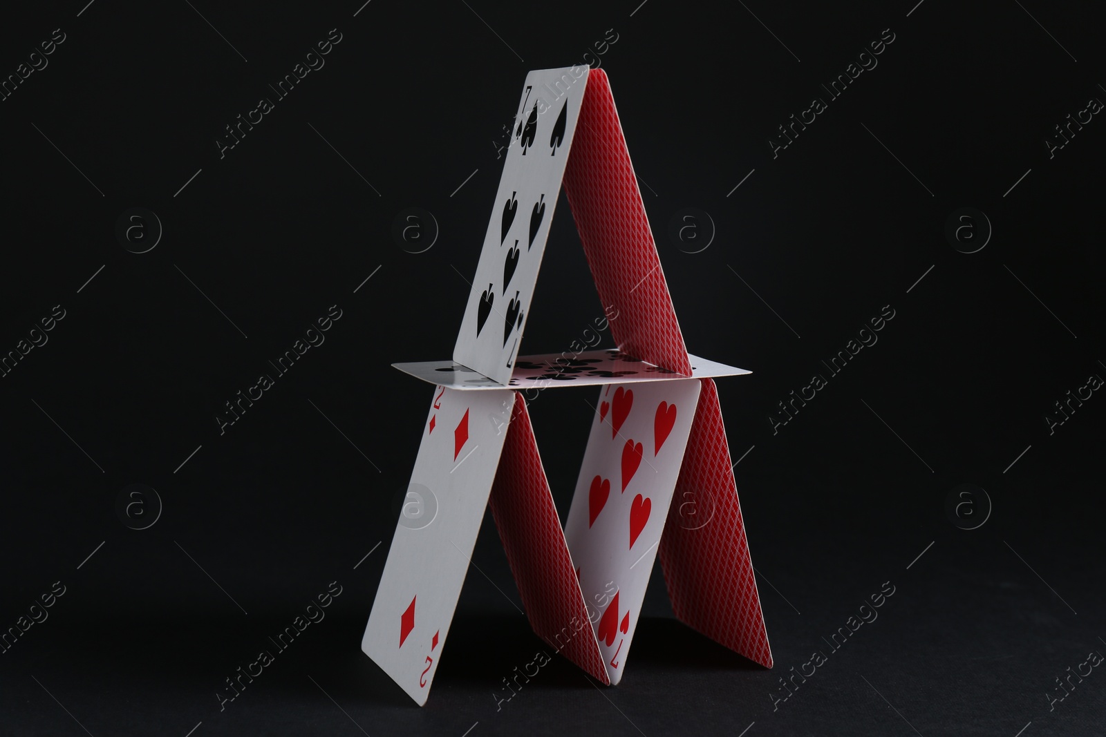 Photo of House of playing cards on black background