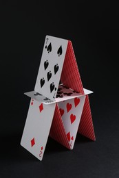 Photo of House of playing cards on black background