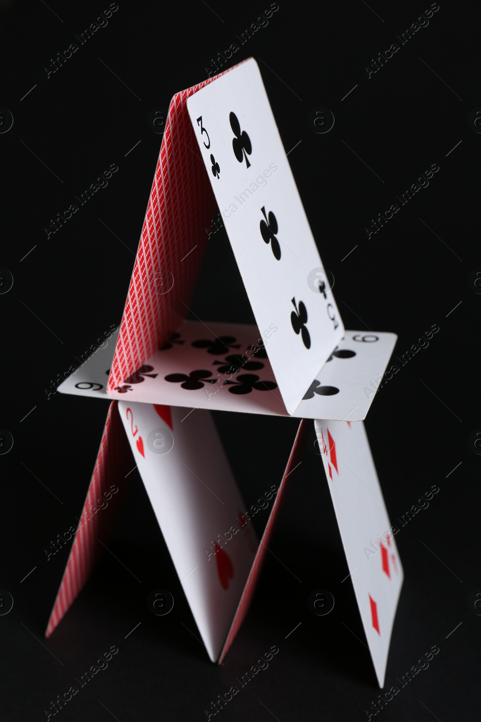 Photo of House of playing cards on black background