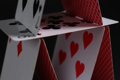 Photo of House of playing cards on black background, closeup