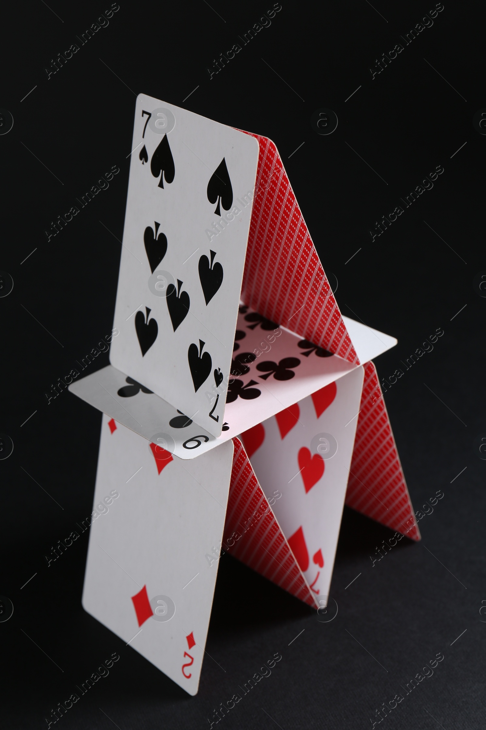 Photo of House of playing cards on black background