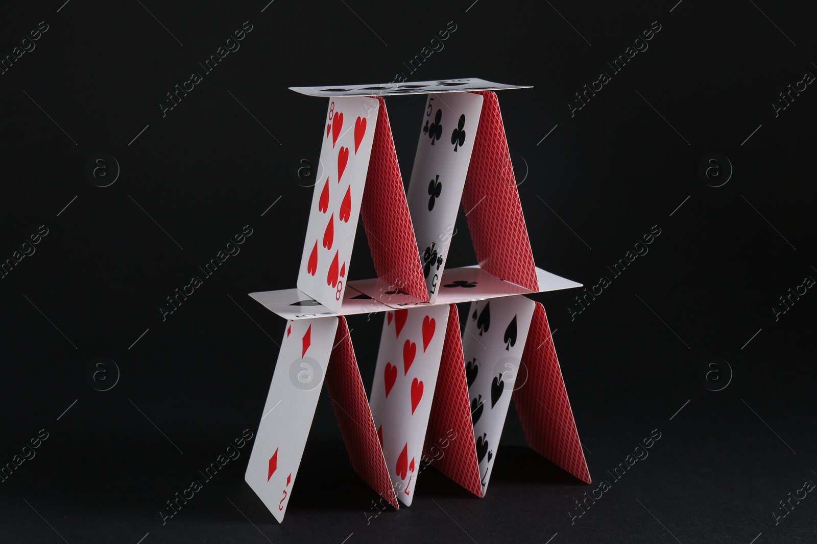 Photo of House of playing cards on black background