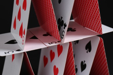 Photo of House of playing cards on black background, closeup