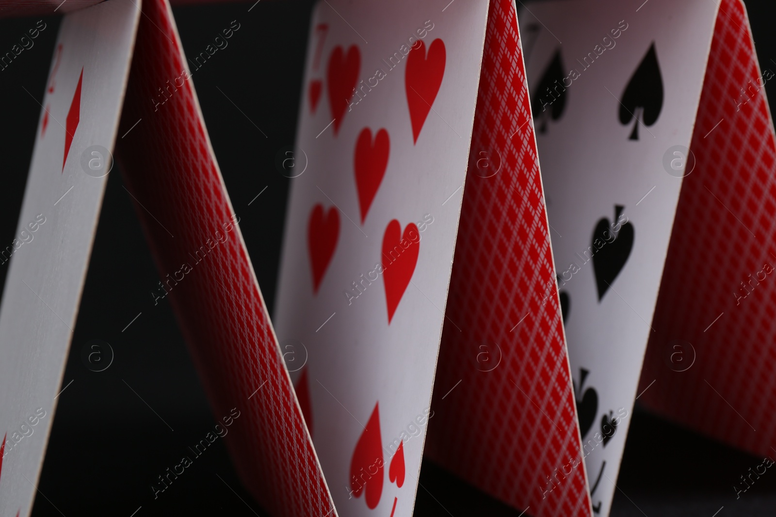 Photo of House of playing cards on black background, closeup