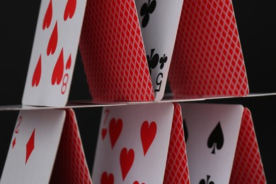 Photo of House of playing cards on black background, closeup