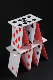 Photo of House of playing cards on black background