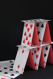 Photo of House of playing cards on black background