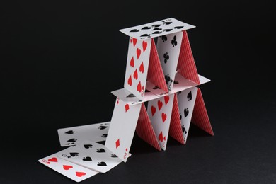 Photo of House of playing cards on black background