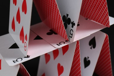 Photo of House of playing cards on black background, closeup