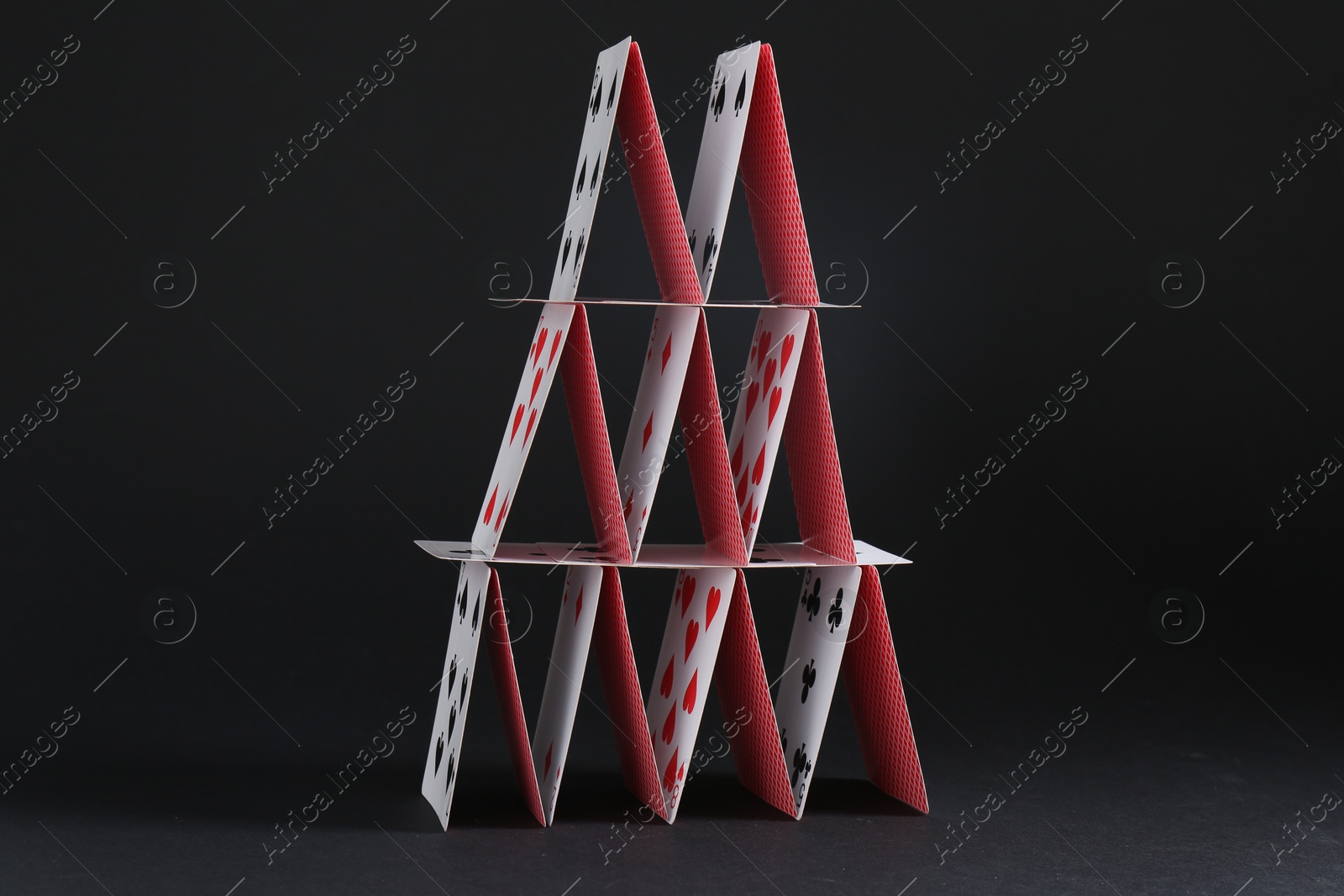 Photo of House of playing cards on black background