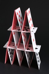 Photo of House of playing cards on black background