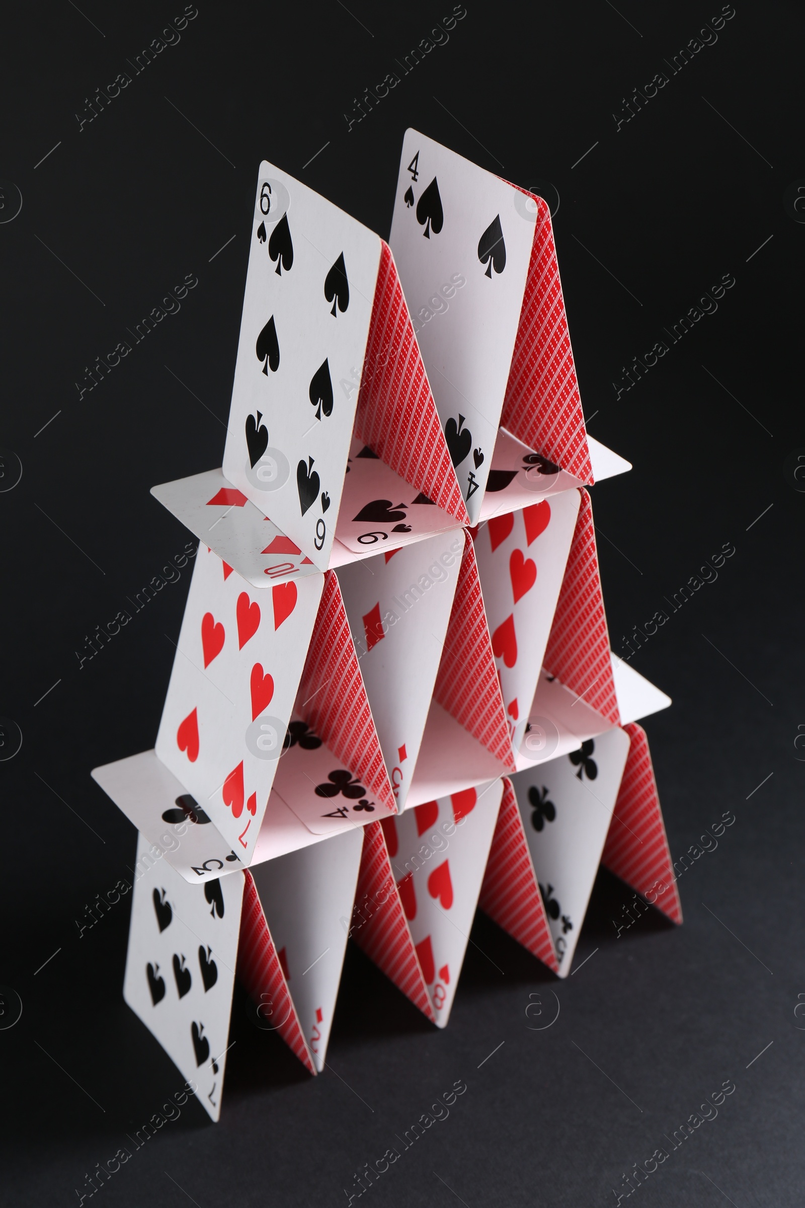 Photo of House of playing cards on black background