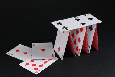 Photo of Collapsed house of playing cards on black background