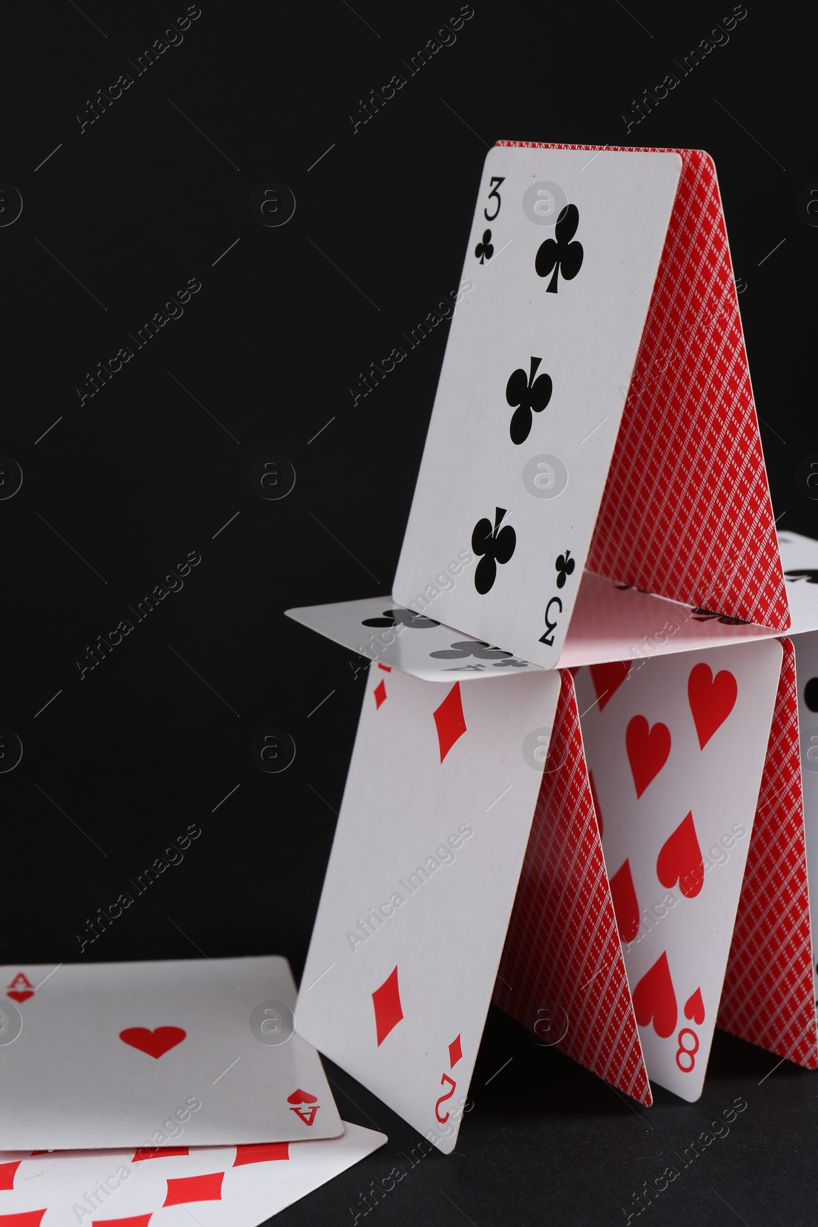 Photo of House of playing cards on black background