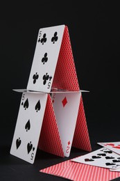 Photo of House of playing cards on black background