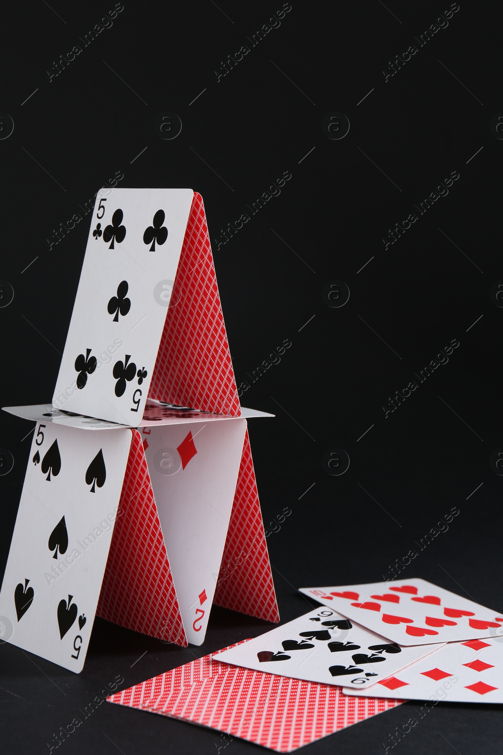 Photo of House of playing cards on black background