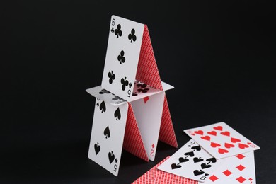 Photo of House of playing cards on black background