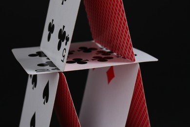 Photo of House of playing cards on black background, closeup