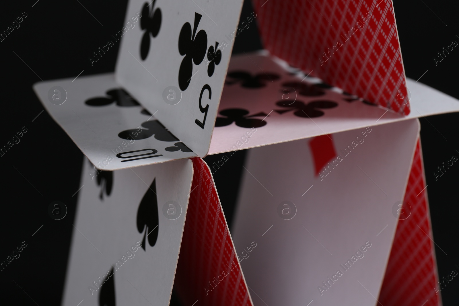 Photo of House of playing cards on black background, closeup