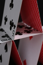 Photo of House of playing cards on black background, closeup