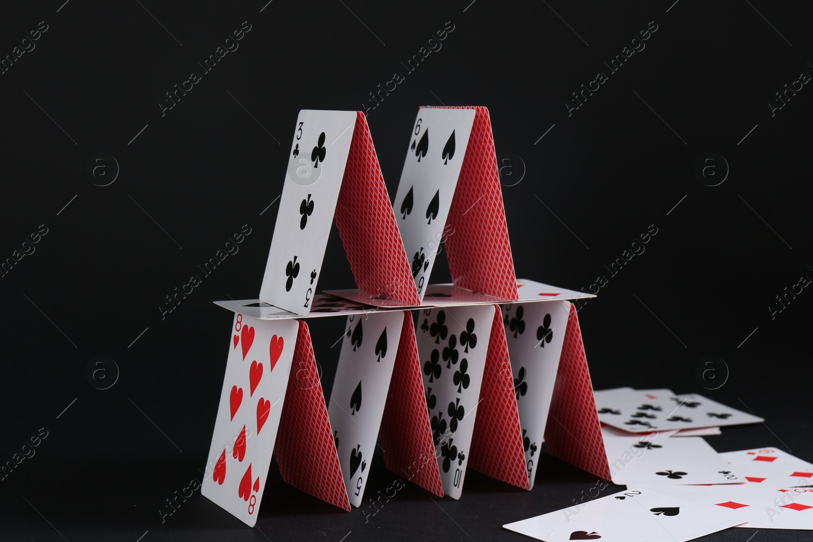 Photo of House of playing cards on black background