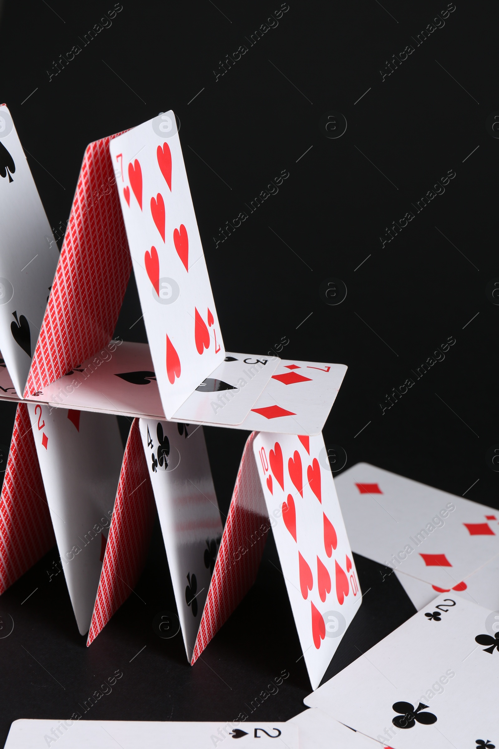 Photo of House of playing cards on black background