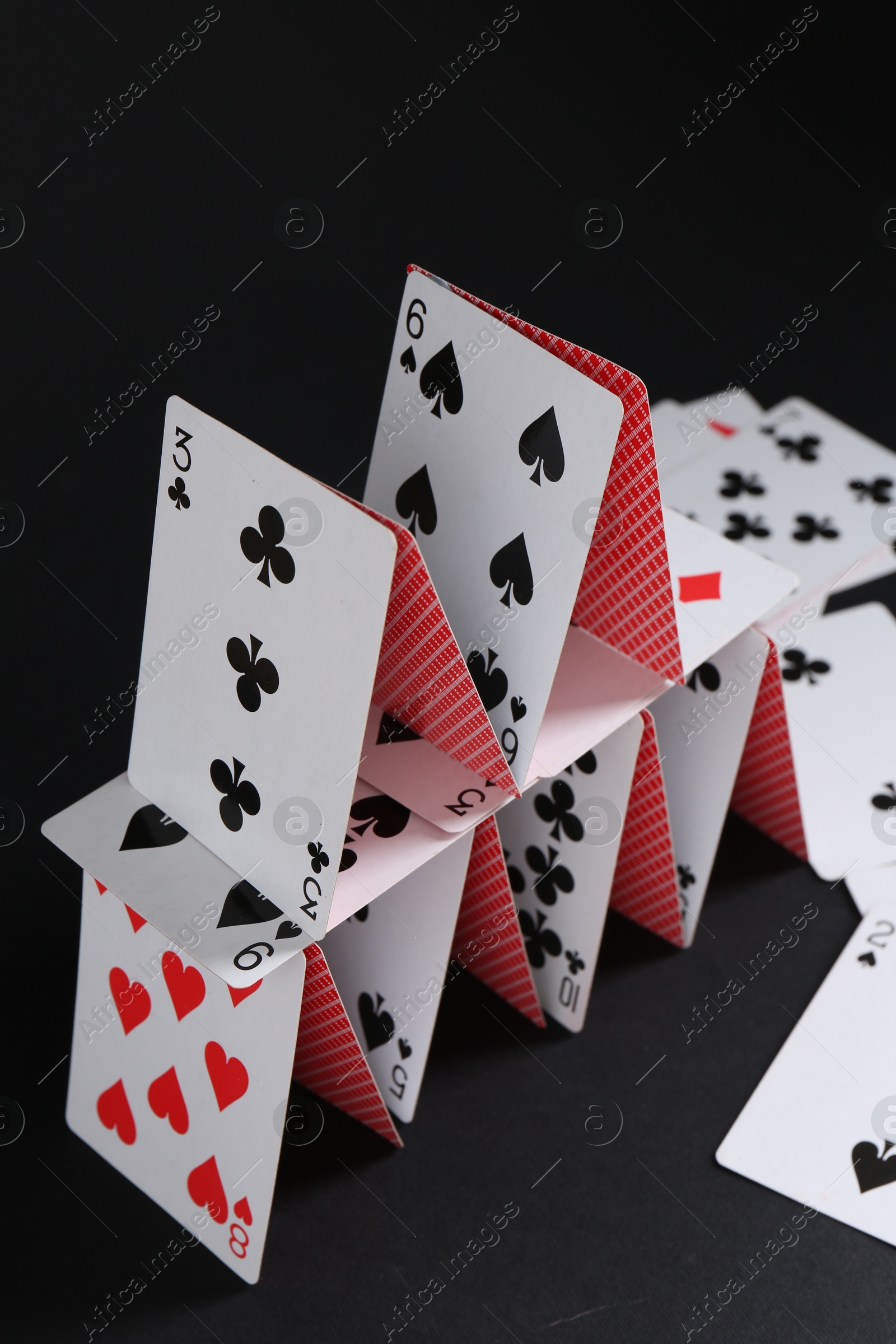 Photo of House of playing cards on black background