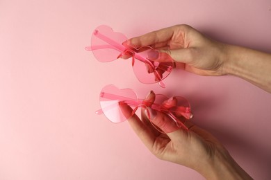 Photo of Woman with stylish heart shaped sunglasses on pink background, top view