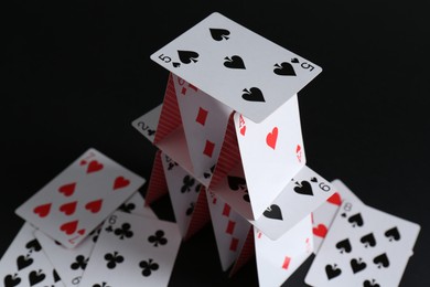 Photo of House of playing cards on black background, closeup