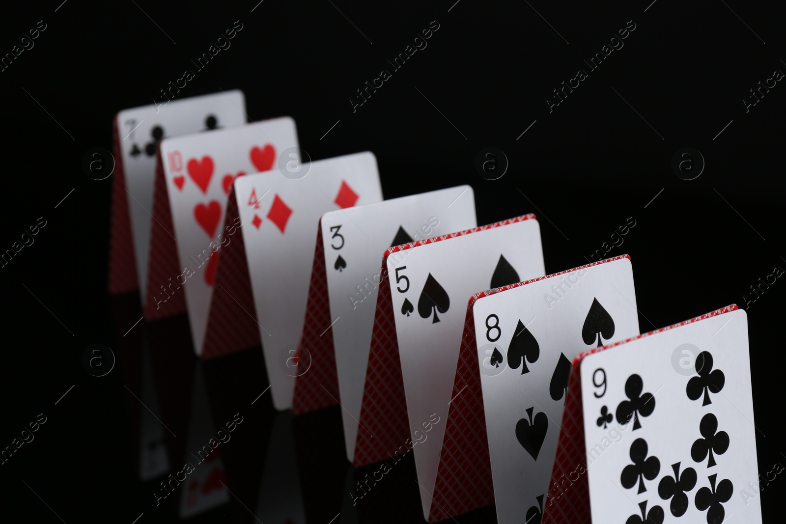 Photo of Row of playing cards on black background, closeup