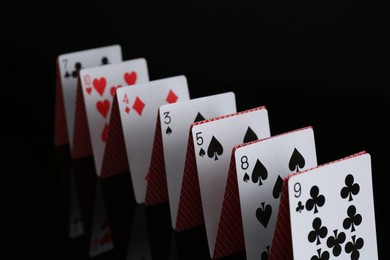 Photo of Row of playing cards on black background, closeup