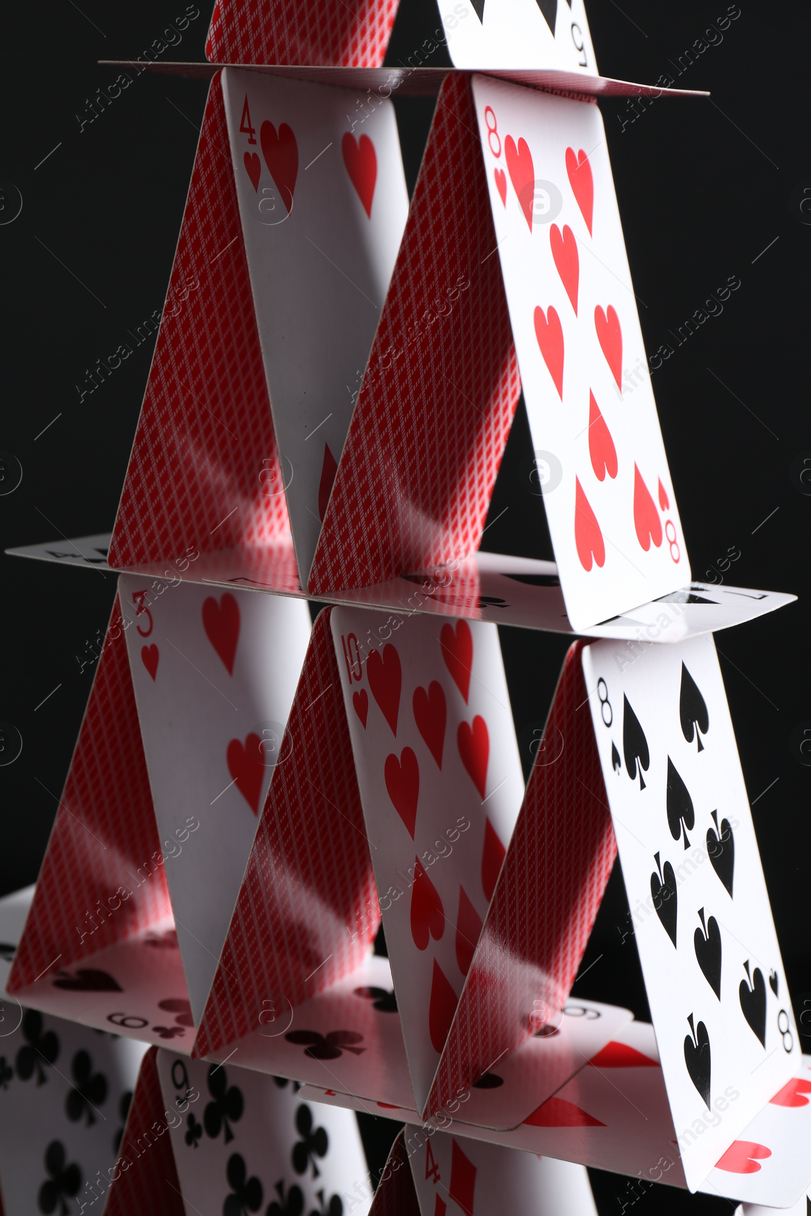 Photo of House of playing cards on black background, closeup