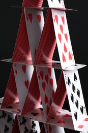 Photo of House of playing cards on black background, closeup