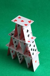 Photo of House of playing cards on green background