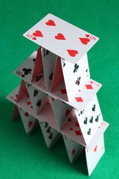 Photo of House of playing cards on green background