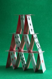 Photo of House of playing cards on green background