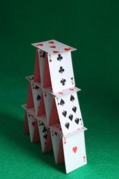 Photo of House of playing cards on green background